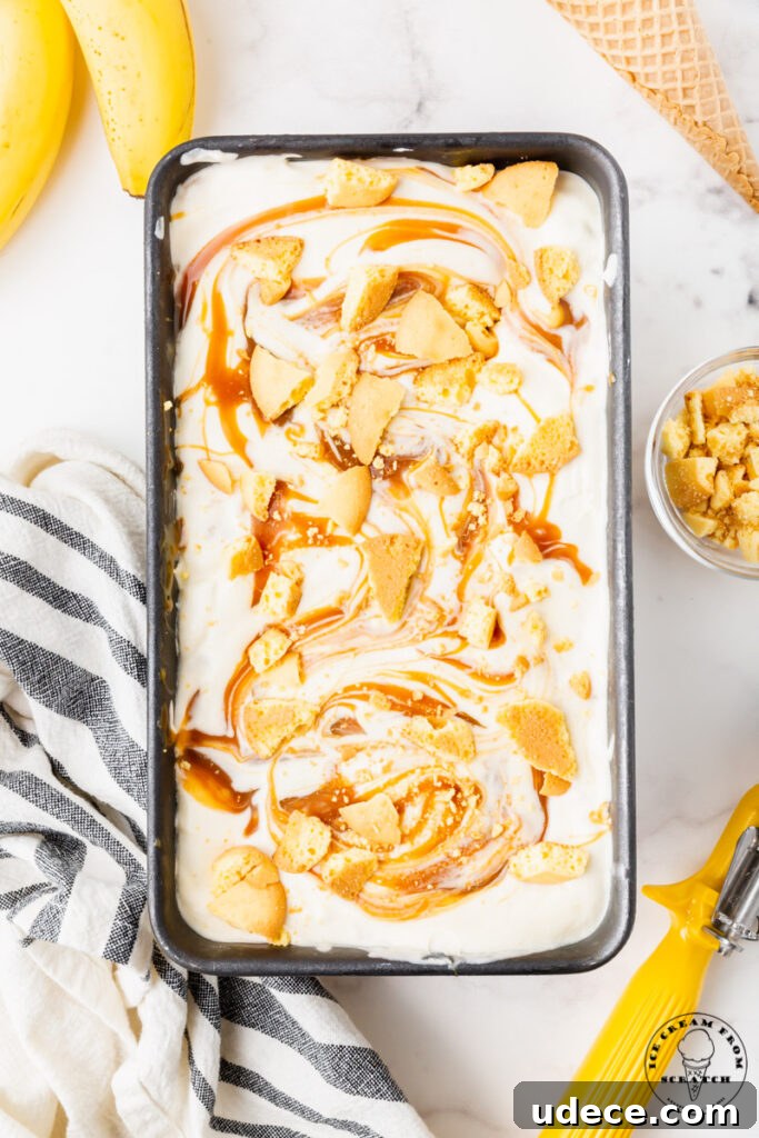 10 Decadent Homemade Ice Cream Recipes to Try Today 2 top down view of a metal loaf pan filled with ice cream swirled with toffee sauce and crushed cookies.