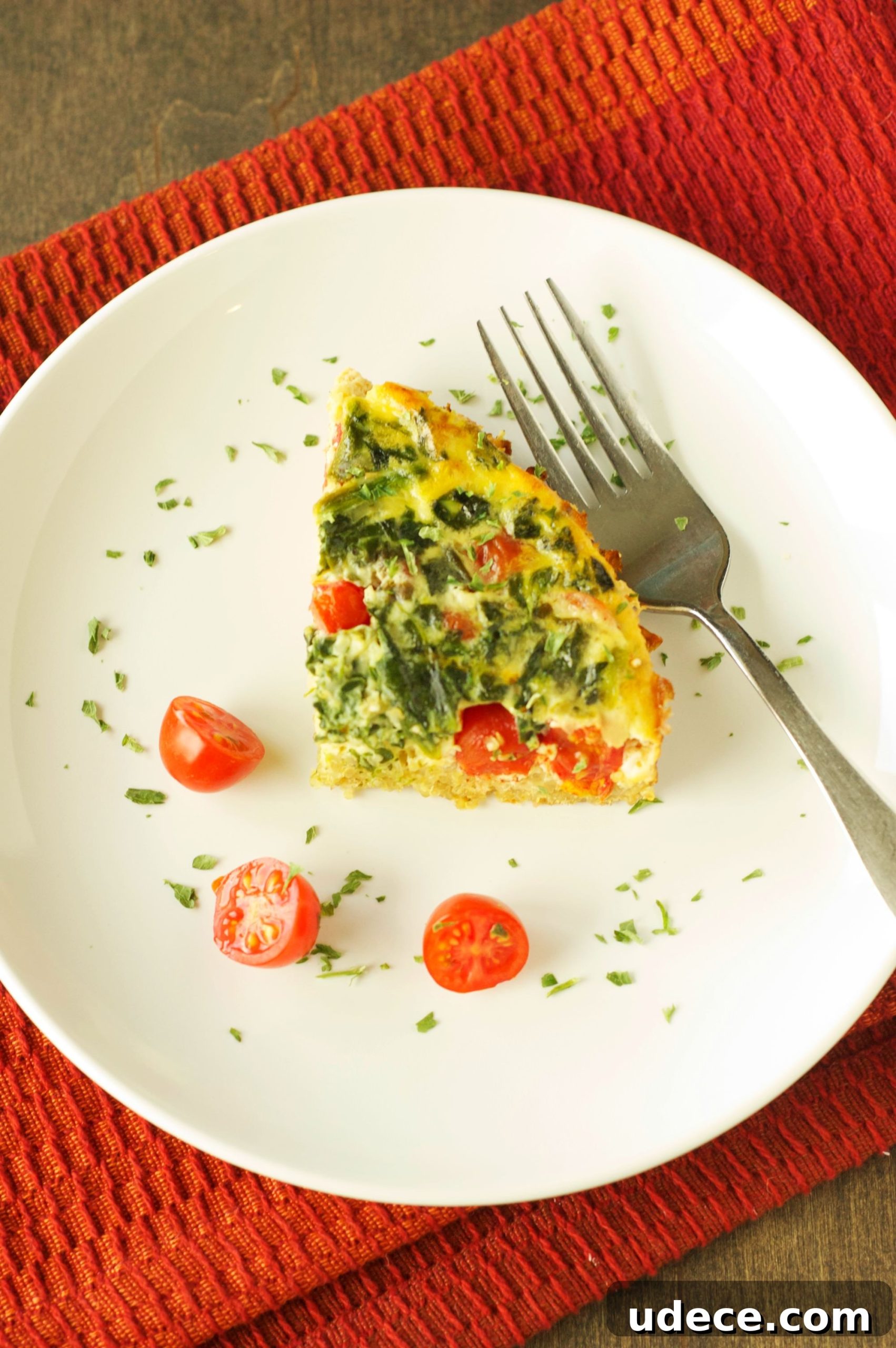 top view of piece of breakfast casserole on white plate with fork on orange napkin