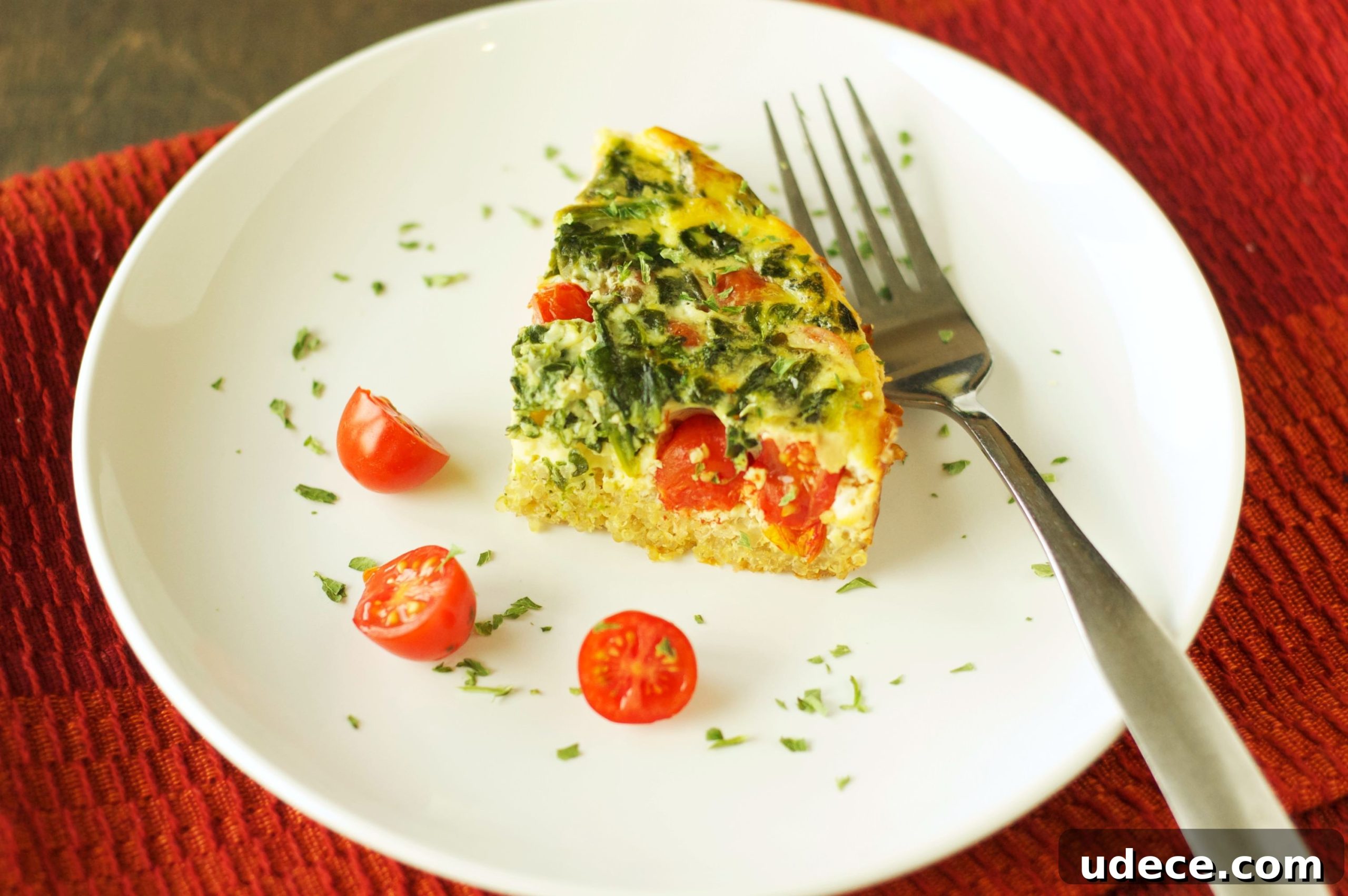 Slow-Cooker Quinoa Breakfast Casserole with Tomato & Spinach 6 piece of breakfast casserole on white plate with fork