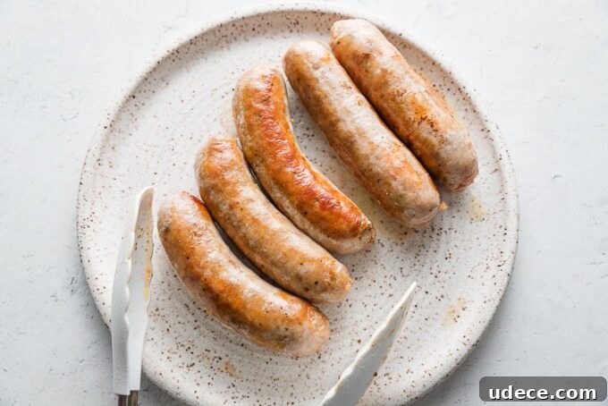 Italian Sausage with Peppers & Onions in Savory Tomato Sauce 3 Browned Italian sausages resting on a white ceramic dinner plate.