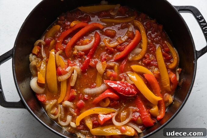 Italian Sausage with Peppers & Onions in Savory Tomato Sauce 5 Tomatoes, broth, and seasonings added to peppers and onions simmering in a skillet.