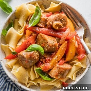 Italian Sausage with Peppers & Onions in Savory Tomato Sauce 9 Bowl full of a one skillet saucy Italian sausage with peppers and onions served over egg noodles with fresh basil to garnish.