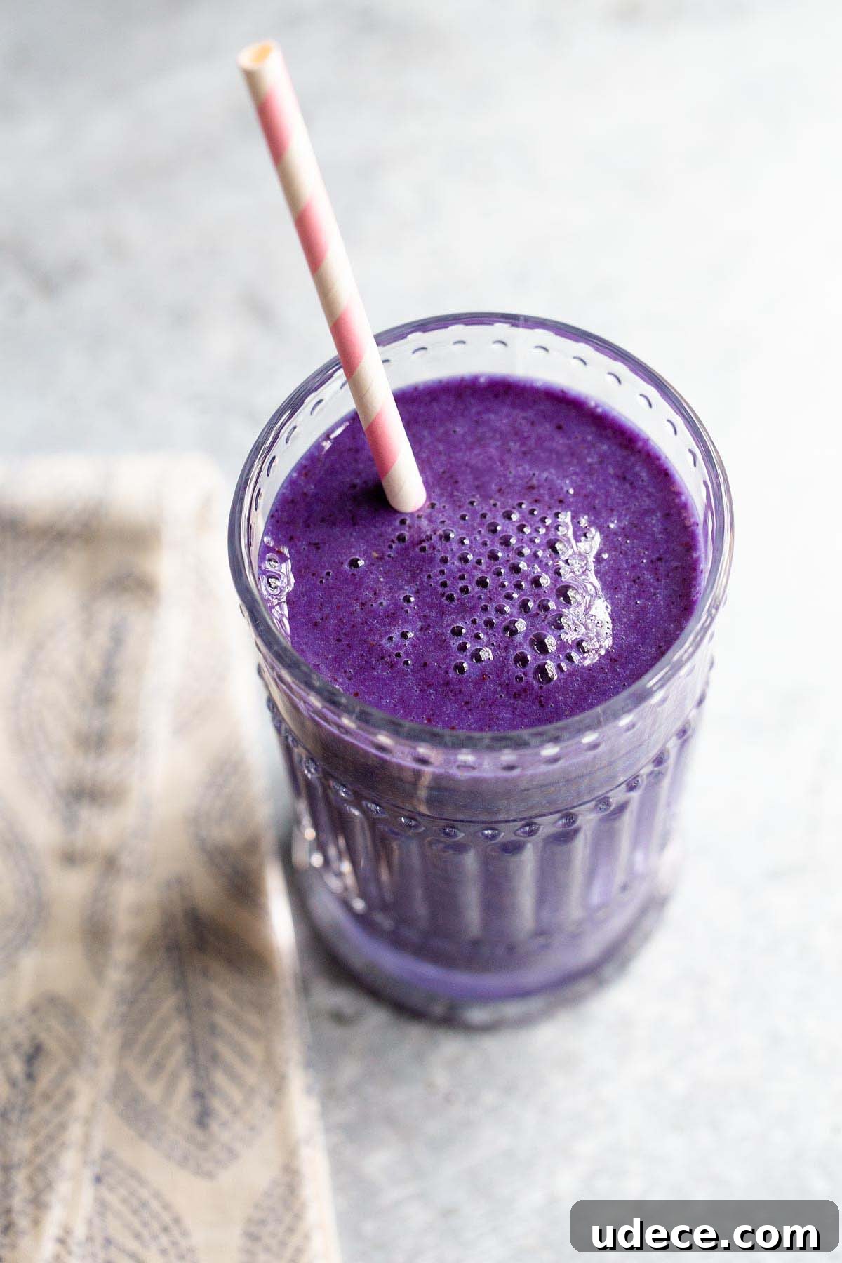 Blue Spirulina Smoothie Recipe for Energy and Glow 2 spirulina smoothie in a glass with a pink and white straw