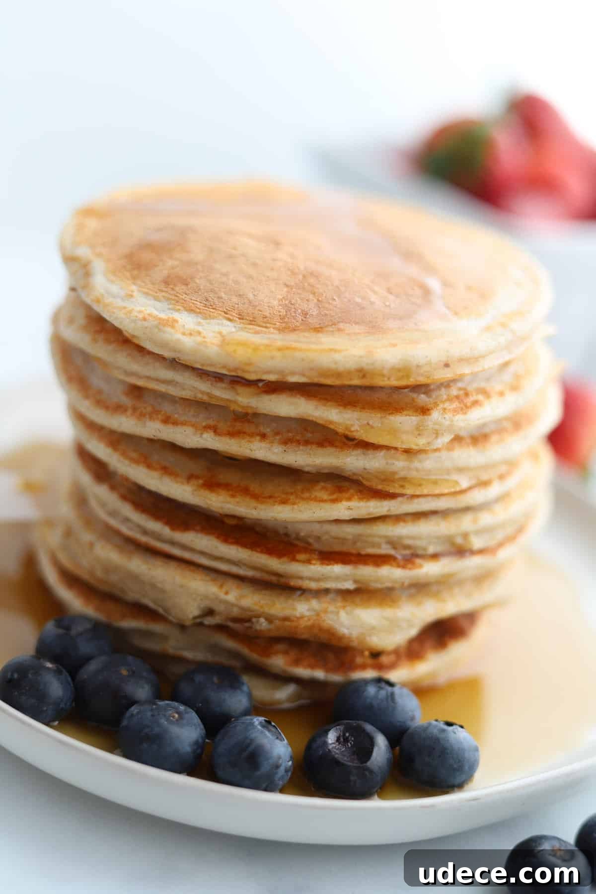 High-Protein Cottage Cheese Pancakes Recipe 5 a stack full of cottage cheese protein pancakes on a plate topped with syrup with blueberries on the side.
