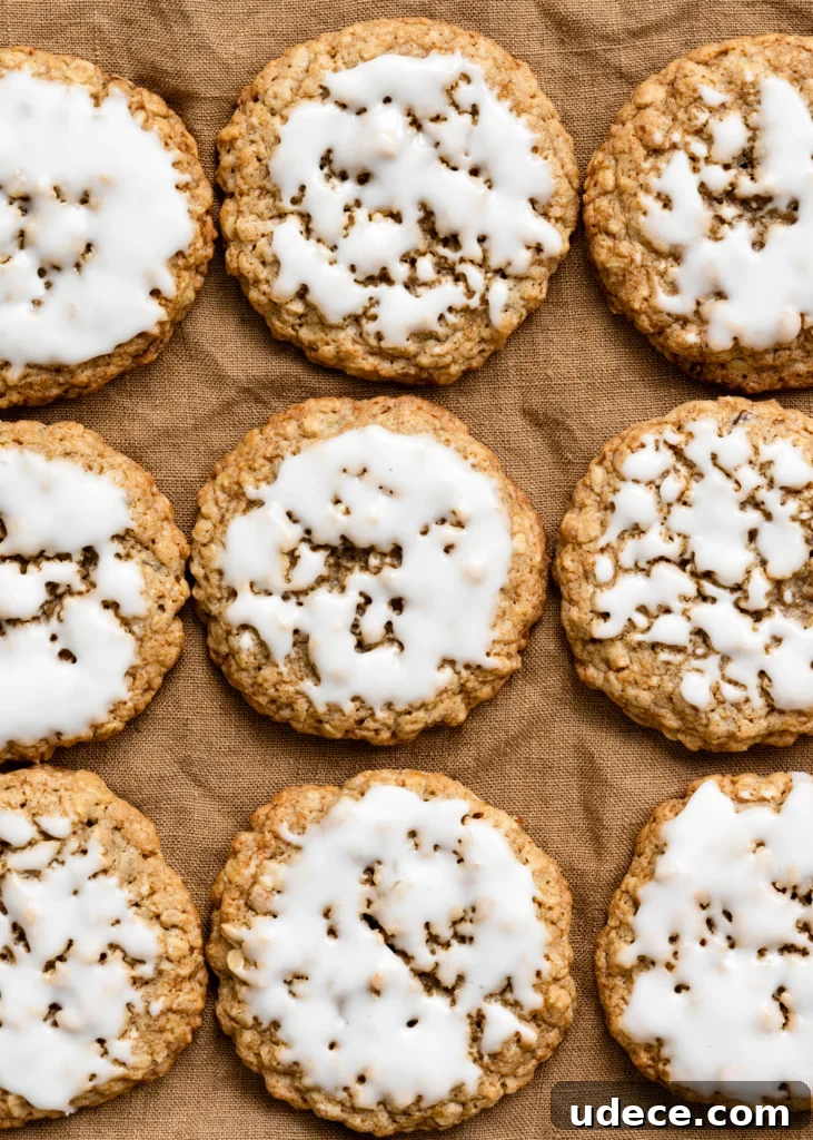 Overhead view of iced oatmeal cookies in rows on a linen cloth.