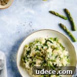 Overhead shot of a single bowl with wild garlic and asparagus risotto with few asparagus tips and lemons on side