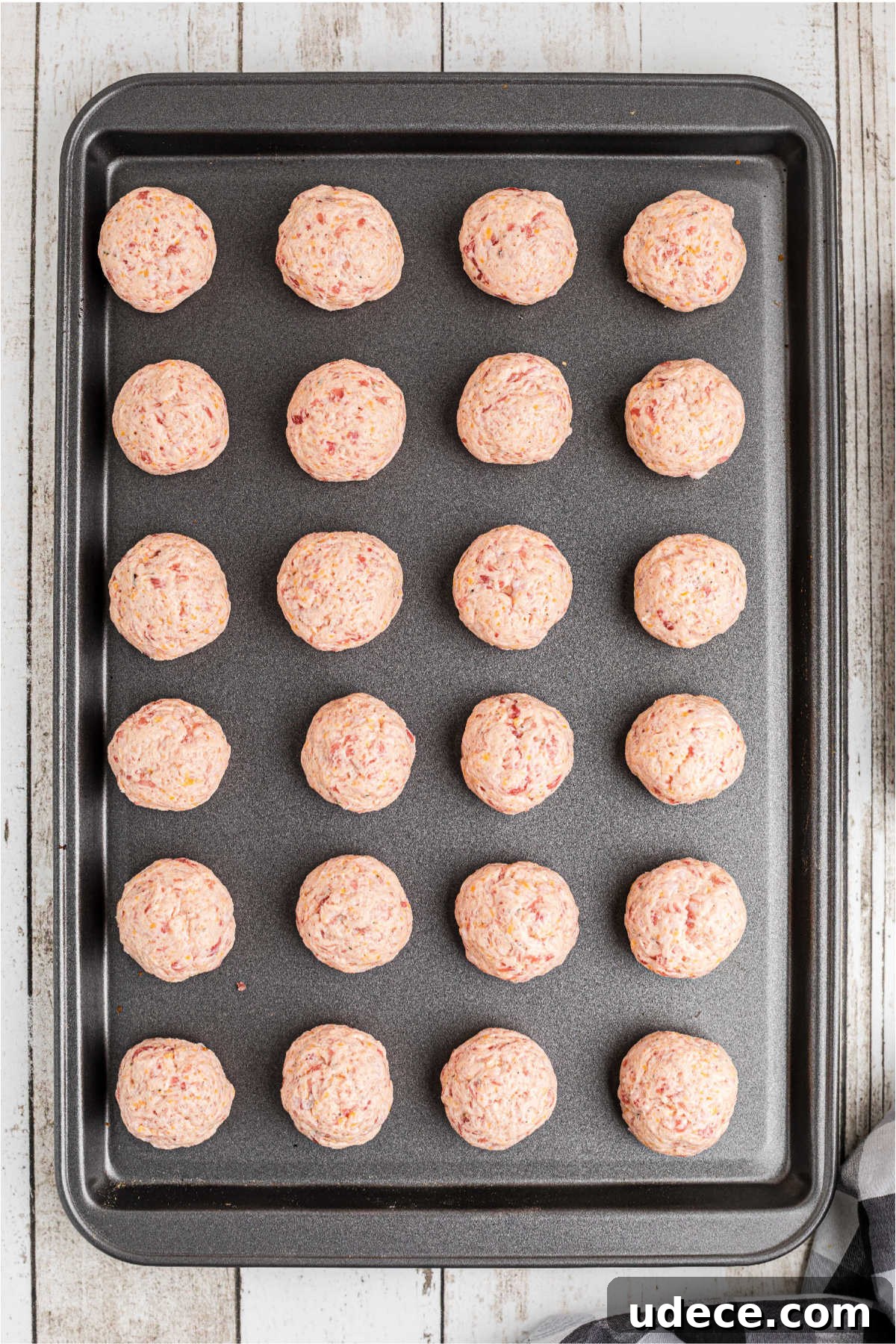 Cheddar Bay-Style Sausage Balls Recipe for Parties and Snacks 5 Sausage balls lined up on a baking sheet.