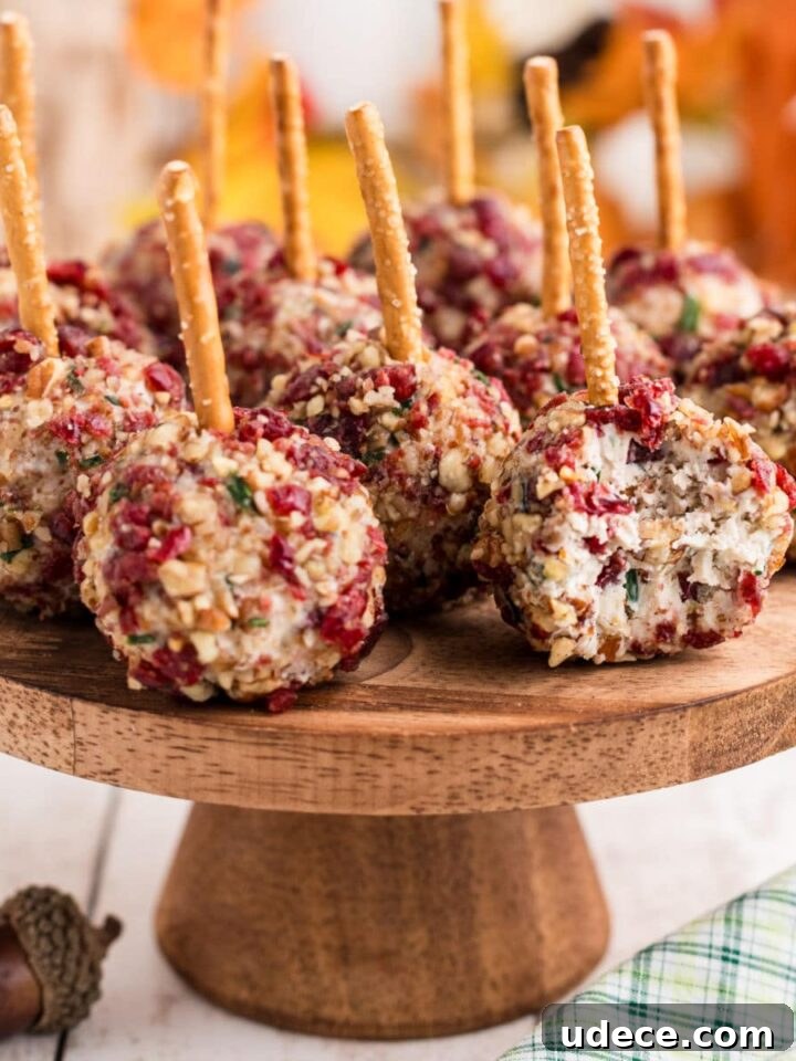 A cake stand full of cranberry pecan cheese ball bites with a bite taken out of one.