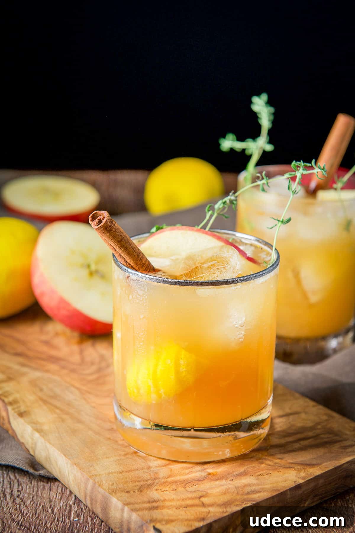 Apple Cider Bourbon Smash Cocktail Recipe 7 two glasses with the apple cider bourbon smash with apples, lemon and cinnamon sticks in them