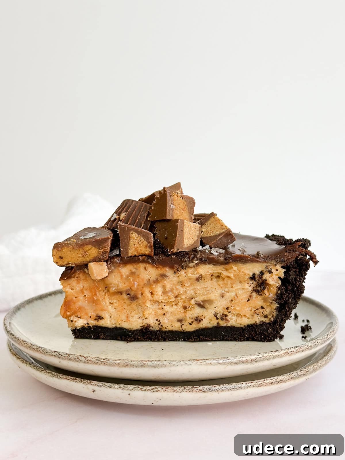 Decadent Peanut Butter Pie with Chocolate Ganache Recipe 2 a whole slice of peanut butter pie with chocolate ganache on a plate topped with reese's pb cups.