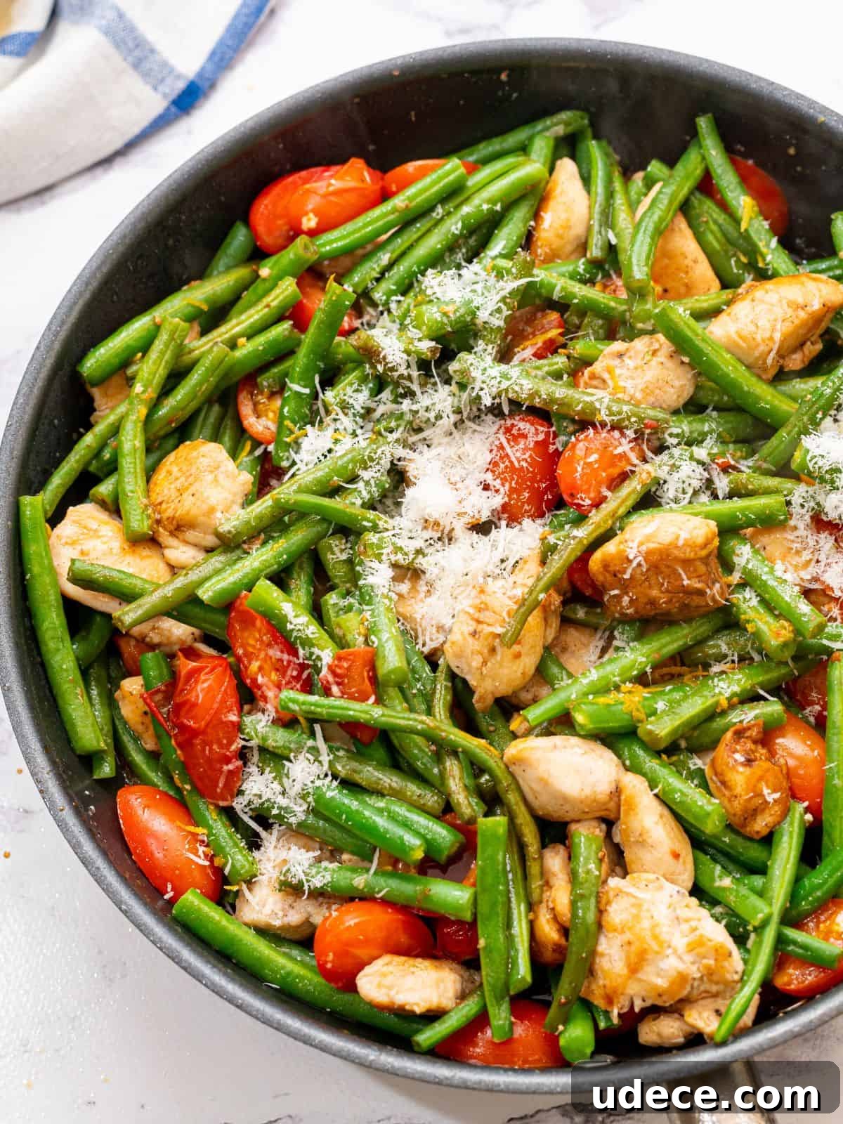 Chicken and Green Beans Large skillet with chunks of chicken, green beans, cherry tomatoes, and parmesan.