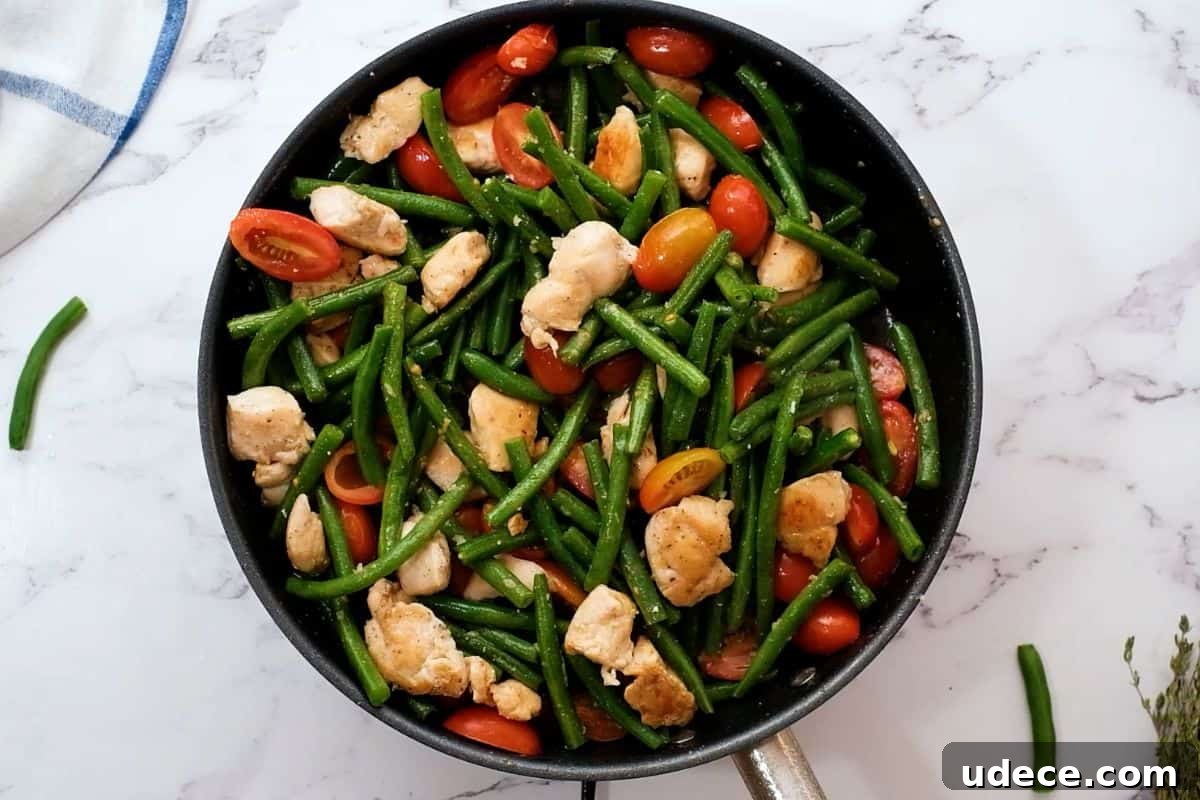 Skillet Chicken Recipe Green beans and tomatoes with chicken in skillet after simmering.