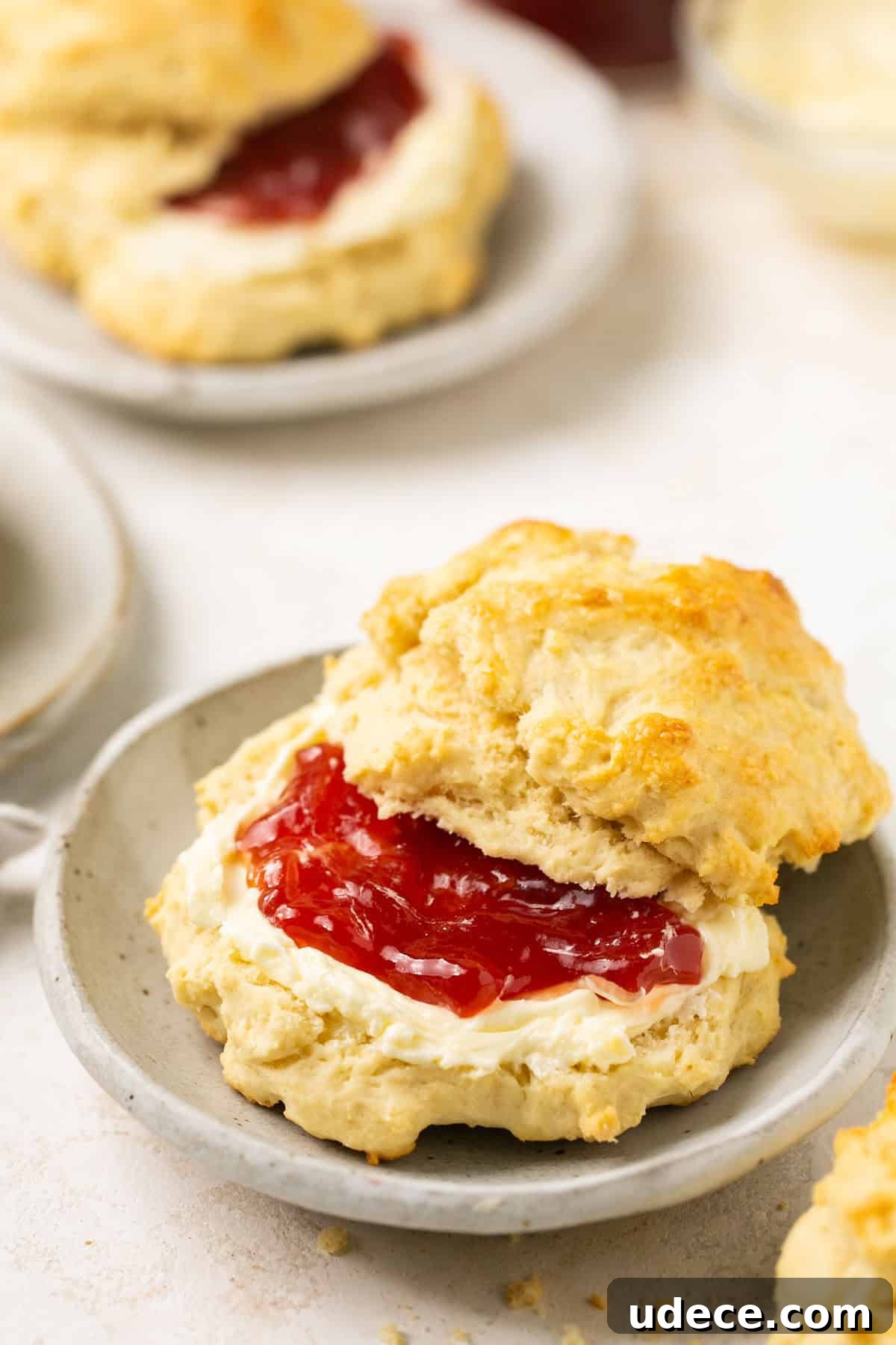 Fluffy Gluten-Free Biscuits with Optional Dairy-Free Version 6 a biscuit cut in half on a gray plate with butter and jam in the middle of it