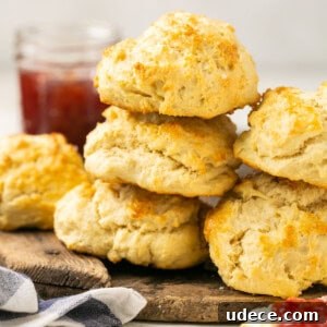 Fluffy Gluten-Free Biscuits with Optional Dairy-Free Version 7 gluten free biscuits stacked on a cutting board with jam in the background