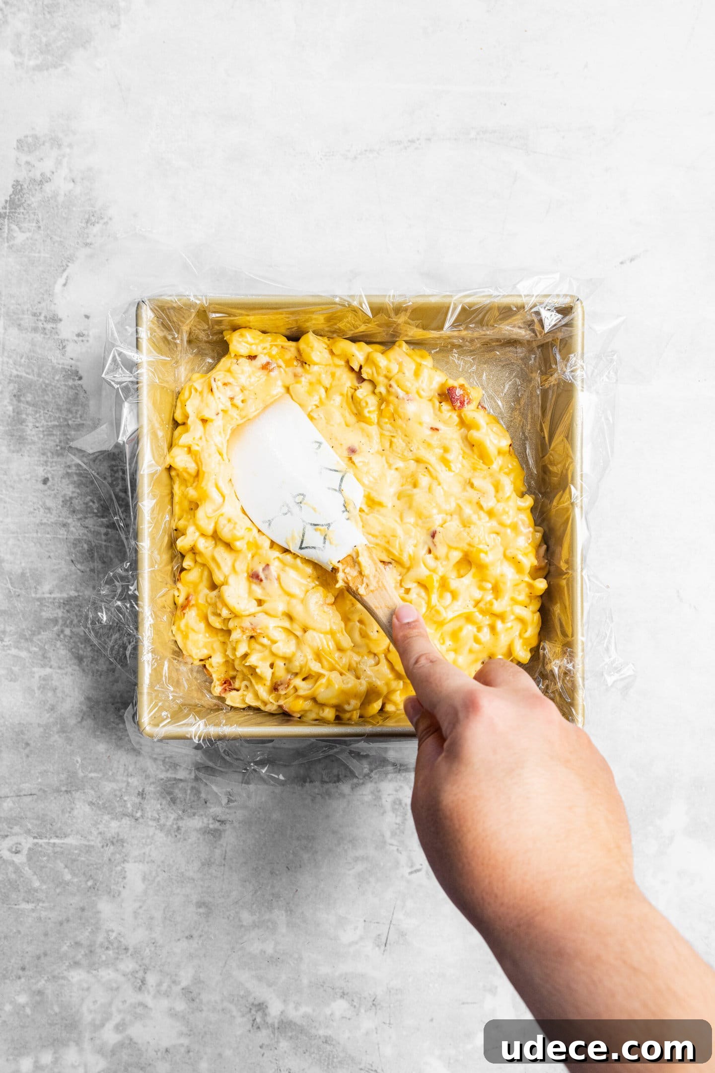 Crispy Homemade Mac and Cheese Bites: Bite-Sized Comfort Food 7 Bacon mac and cheese being pressed into lined baking pan.