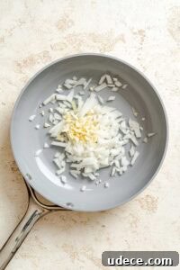 Creamy Apple Curry Recipe with Warm Spices and Coconut Milk 12 Process shot showing ingredients cooking on pan.