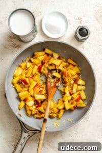 Creamy Apple Curry Recipe with Warm Spices and Coconut Milk 13 Process shot showing ingredients cooking on pan.