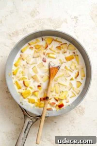 Creamy Apple Curry Recipe with Warm Spices and Coconut Milk 14 Process shot showing stirring ingredients in pan.