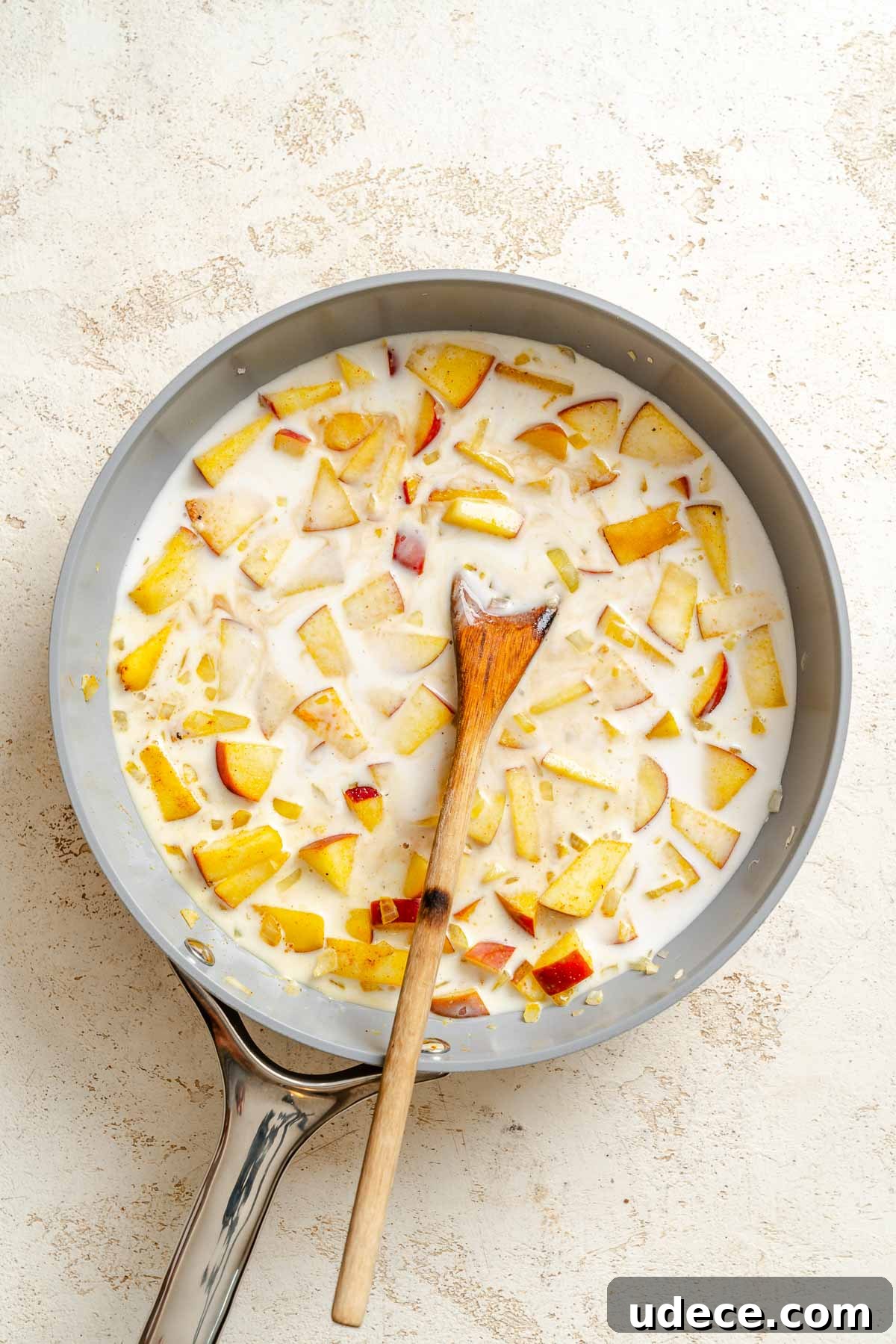 Creamy Apple Curry Recipe with Warm Spices and Coconut Milk 7 Process shot showing stirring ingredients in pan.