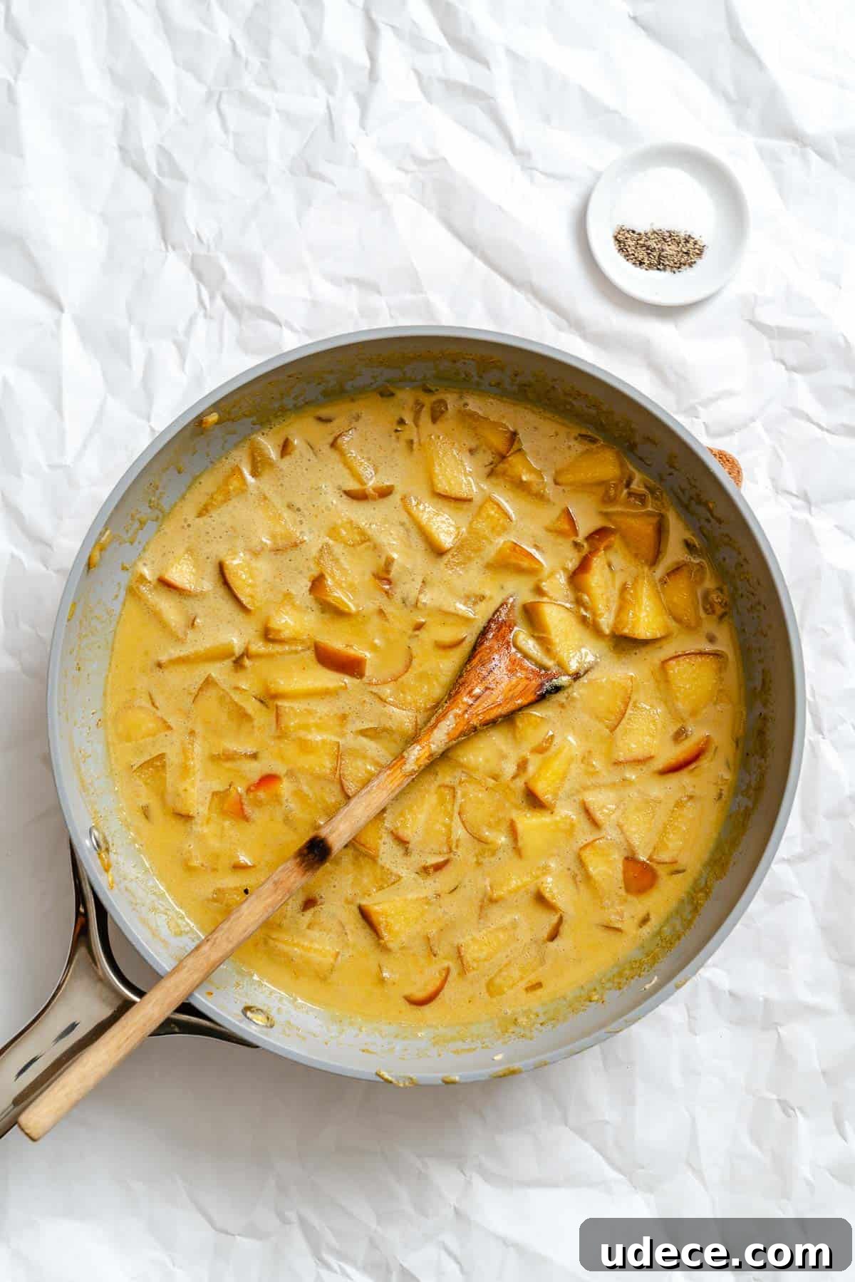 Creamy Apple Curry Recipe with Warm Spices and Coconut Milk 8 Process shot showing stirring ingredients in pan.