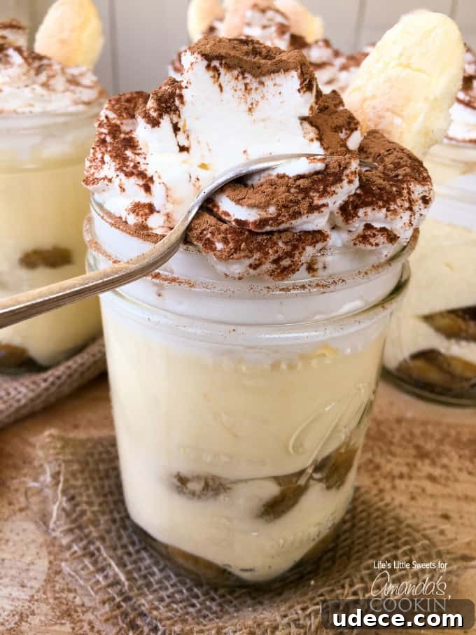 A close up photo of a tiramisu trifle in a mason jars with a spoon.