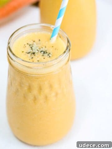 One Carrot Banana Smoothie in a glass jar with a blue and white striped straw.