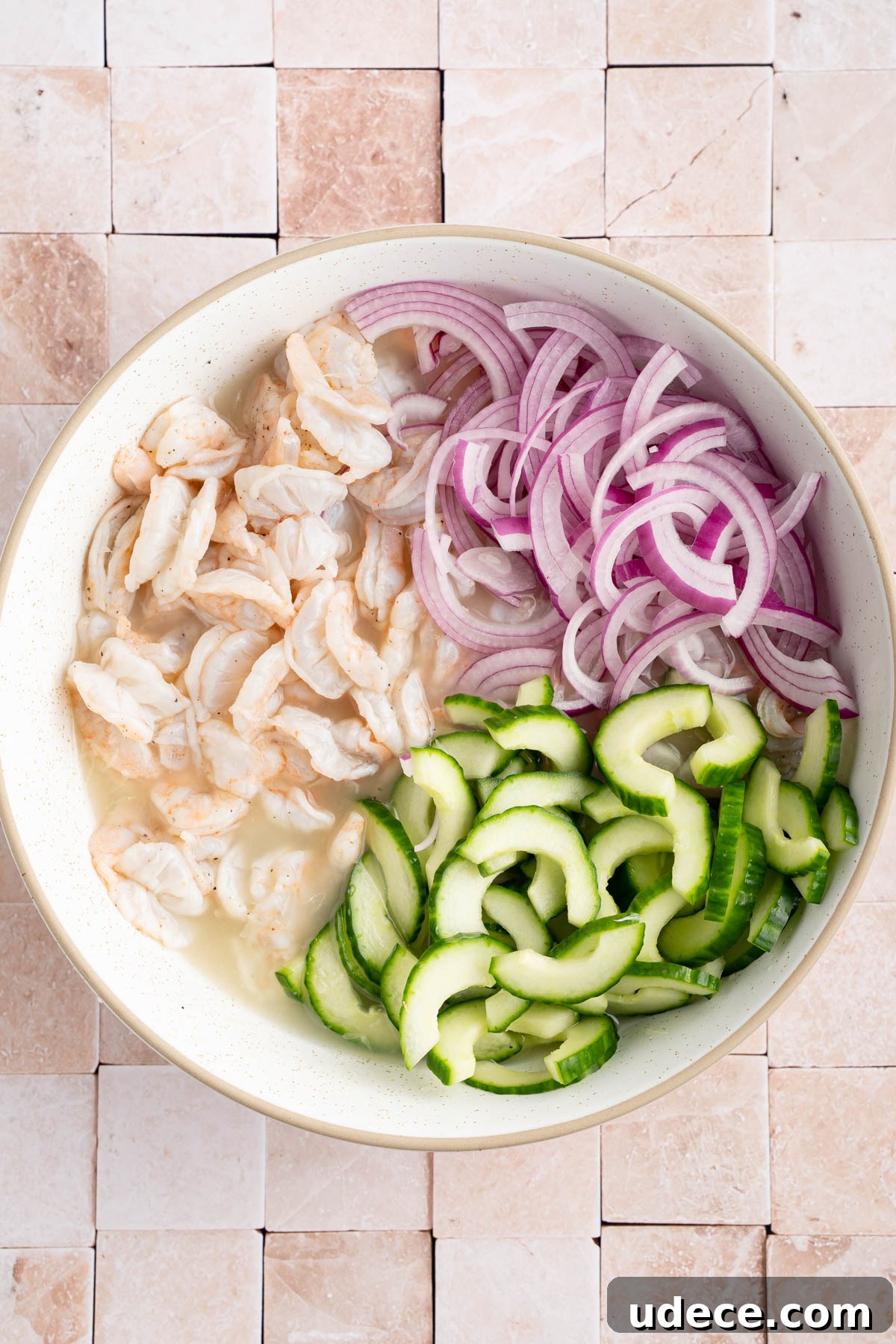 Aguachile de Camarón: Spicy Mexican Shrimp Recipe 6 The cooked shrimp, red onion and cucumber in a large bowl before mixing.