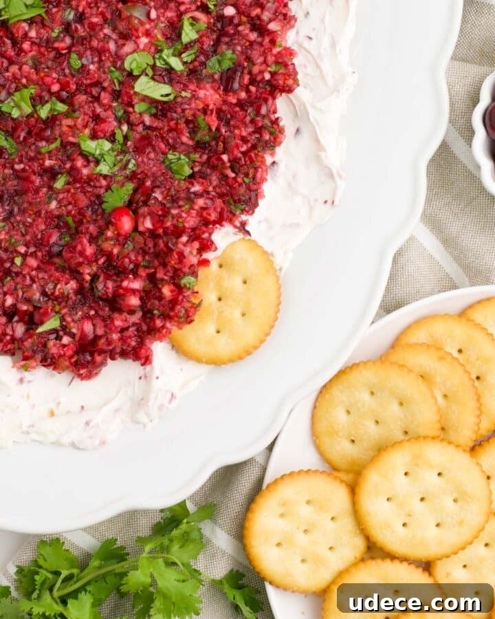 A white platter of cranberry jalapeno dip with crackers.