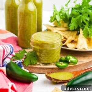 Homemade Jalapeño Hot Sauce Recipe for Bold Heat and Flavor 15 A small jar of jalapeno hot sauce on the table in front with fresh ingredients around it on the table top.