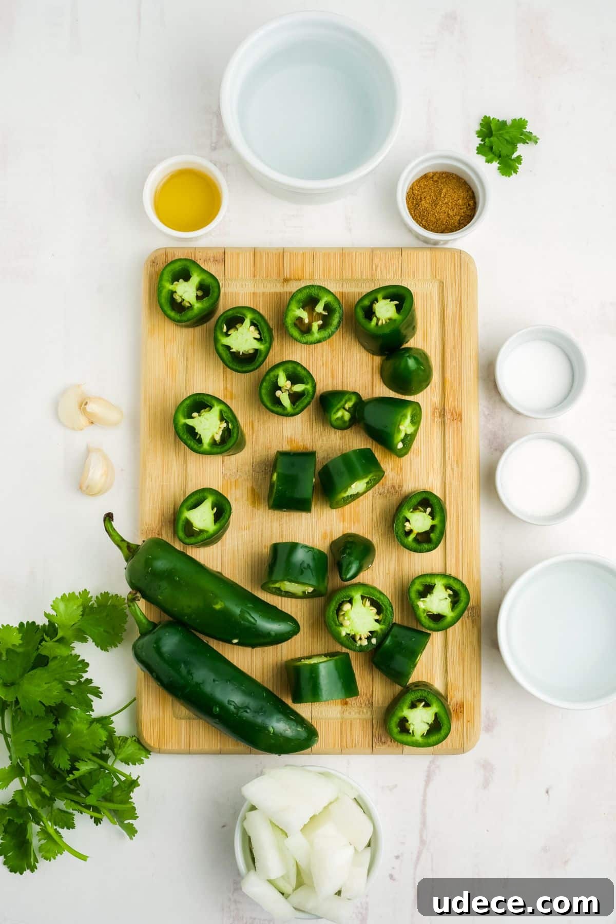 Homemade Jalapeño Hot Sauce Recipe for Bold Heat and Flavor 4 Jalapenos cut on a cutting board with other ingredients surrounding the cutting board.
