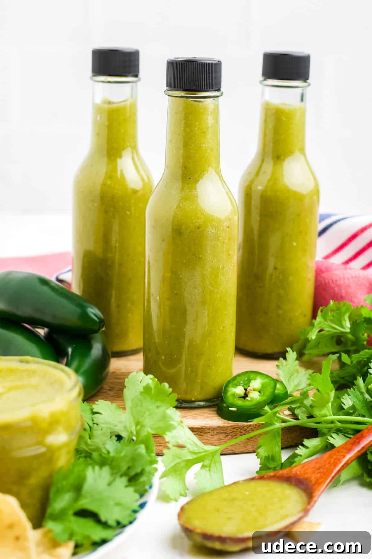 Homemade Jalapeño Hot Sauce Recipe for Bold Heat and Flavor 9 Hot sauce in bottles on the table with cilantro and lime halves.