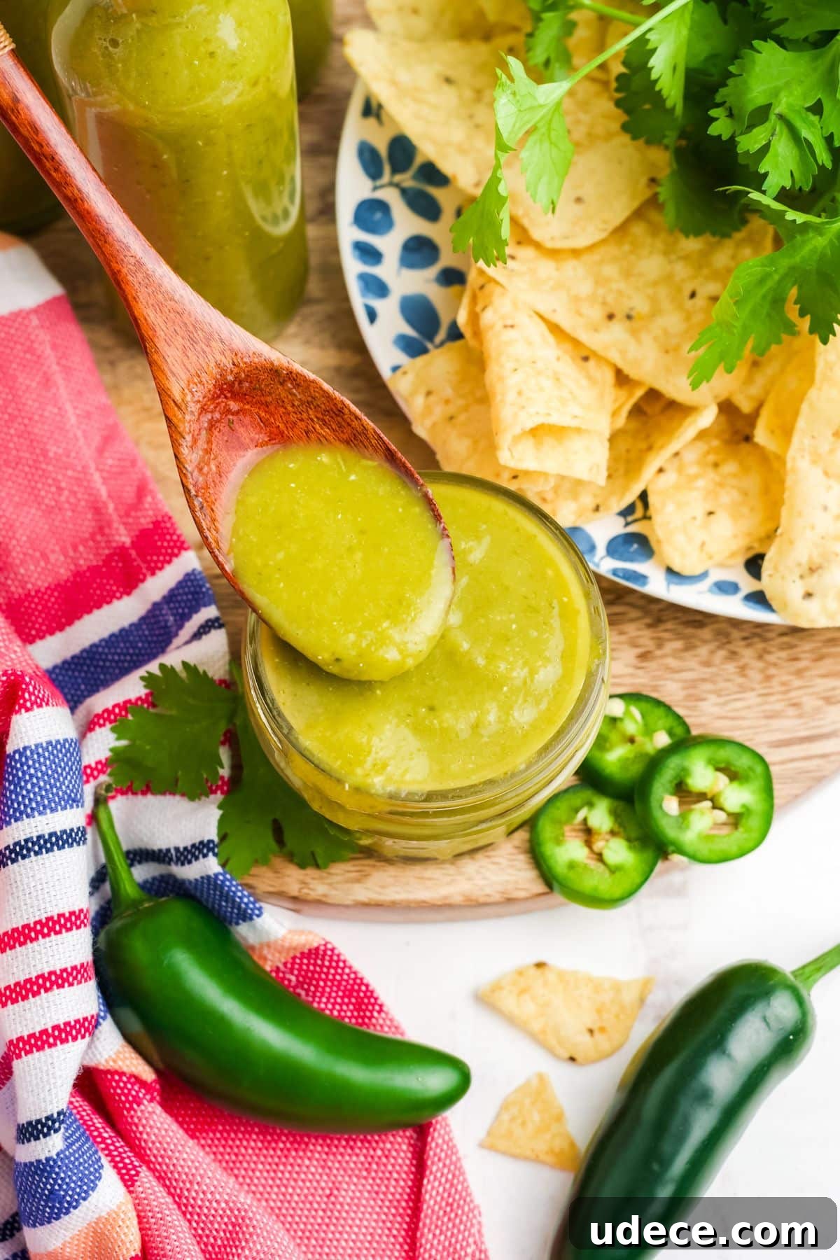 Homemade Jalapeño Hot Sauce Recipe for Bold Heat and Flavor 10 A wooden spoonful of jalapeno hot sauce held up over a small jar on the table.