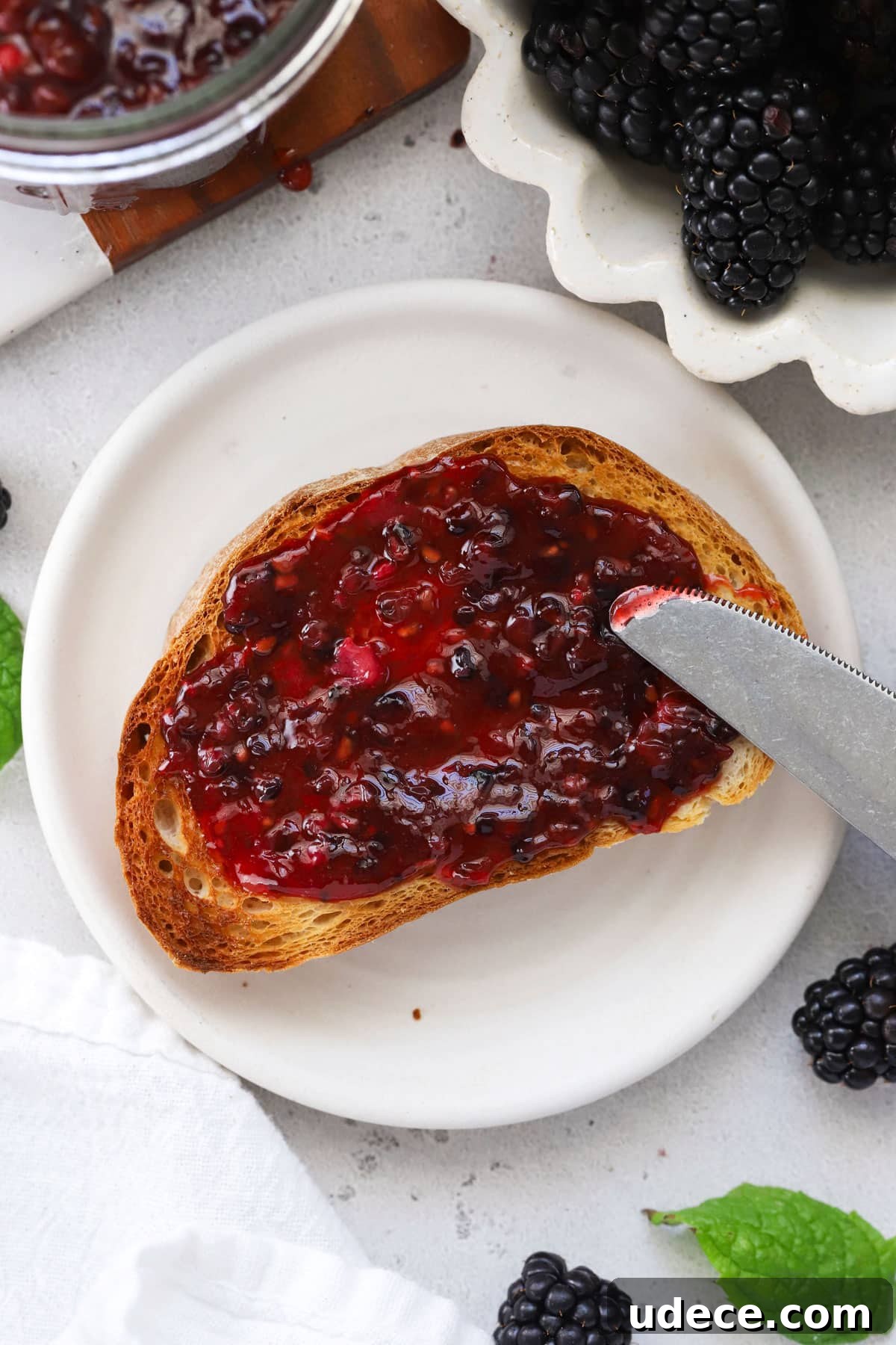 Blackberry Freezer Jam Recipe: Quick No-Cook Preserve 7 Spreading blackberry freezer jam on a slice of toast