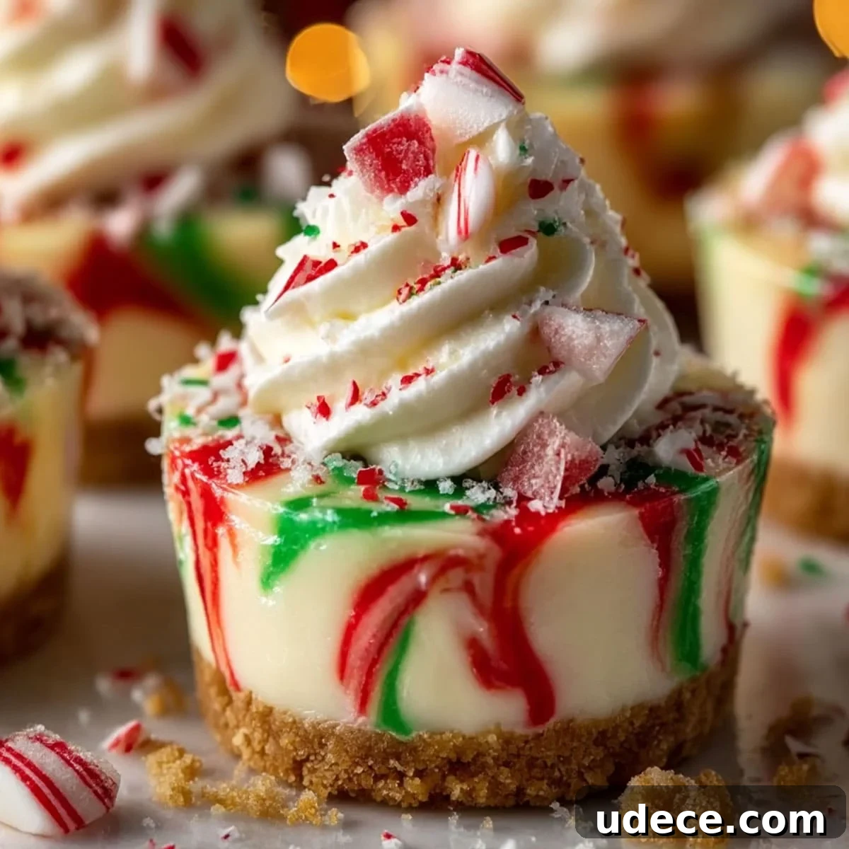 Mini no bake cheesecakes with swirled red and green filling and whipped topping