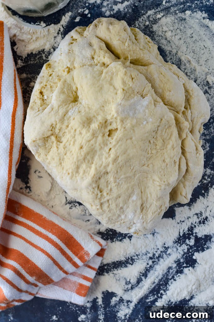 Perfect Homemade Cinnamon Rolls Recipe for Soft, Gooey Swirls 3 Bread dough on a floured surface with an orange and white striped towel.