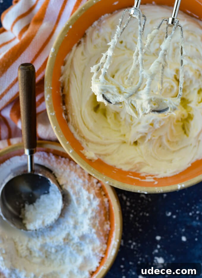 Perfect Homemade Cinnamon Rolls Recipe for Soft, Gooey Swirls 9 A bowl of icing with beaters and a bowl of powdered sugar and an orange and white striped towel.