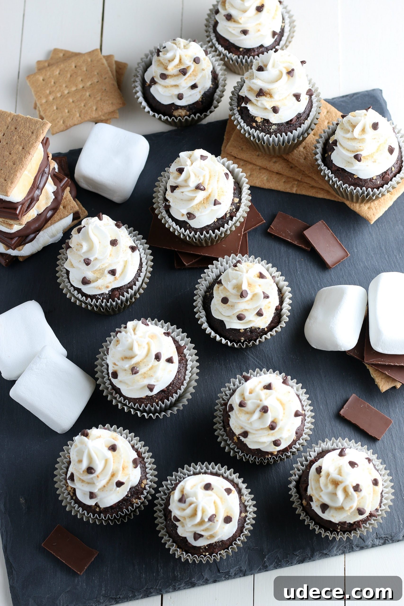 S’mores Cupcakes from Cake Mix: Quick Campfire Dessert Recipe 10 finished s'more cupcake recipe with cake mix with graham crackers, chocolate, and marshmallows on a grey cutting board.