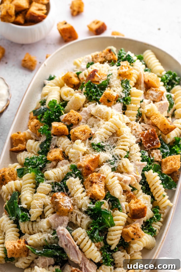 Creamy Chicken Caesar Pasta Salad arranged on a serving platter with kale, Parmesan, and homemade croutons.