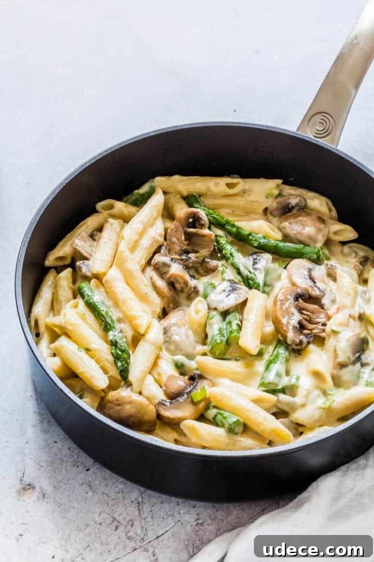 Black skillet containing mushroom asparagus pasta in a sauce