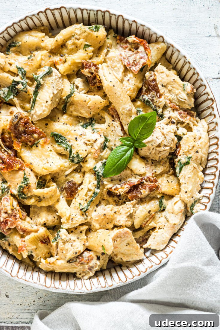 A bowl of slow cooker Tuscan chicken pasta garnished with basil