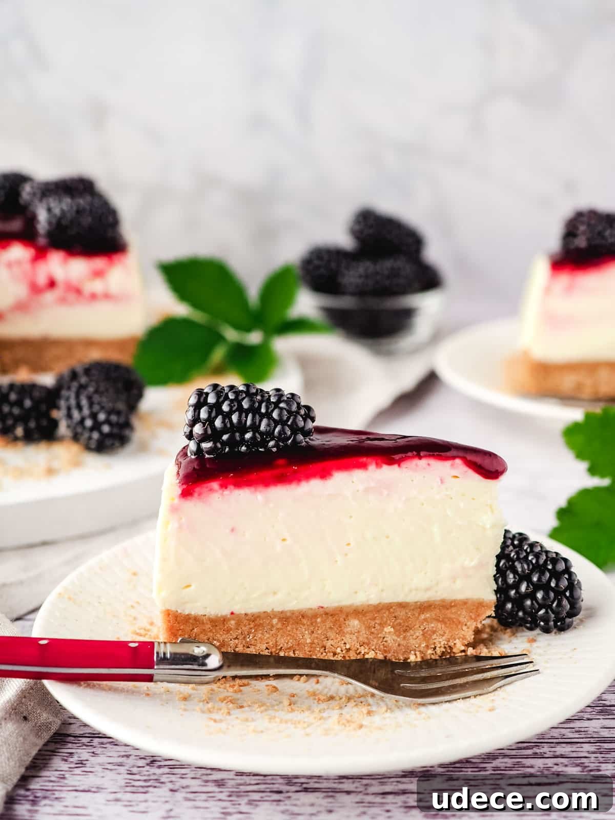 Decadent Blackberry Cheesecake Recipe with Fresh Fruit Topping 11 Slice of no bake blackberry cheesecake on a plate with fork, and rest of cake in background.