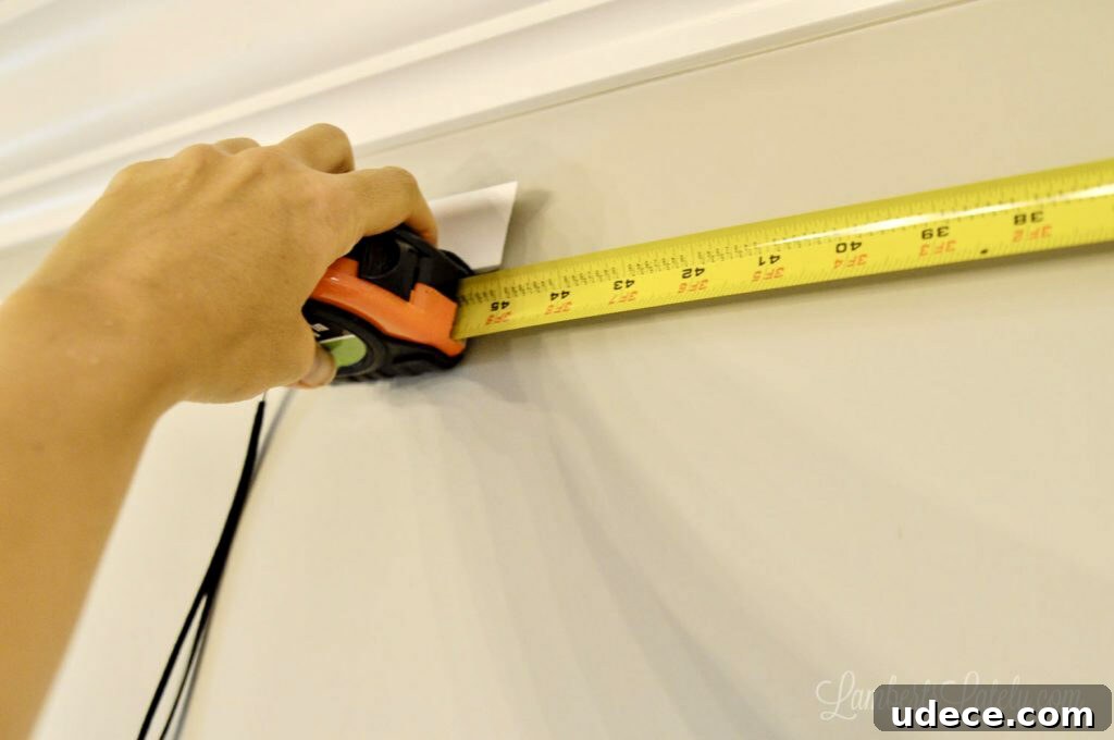 DIY Faux Crown Molding Guide: Simple Beginner-Friendly Hack 7 measuring molding on a wall with a tape measure.