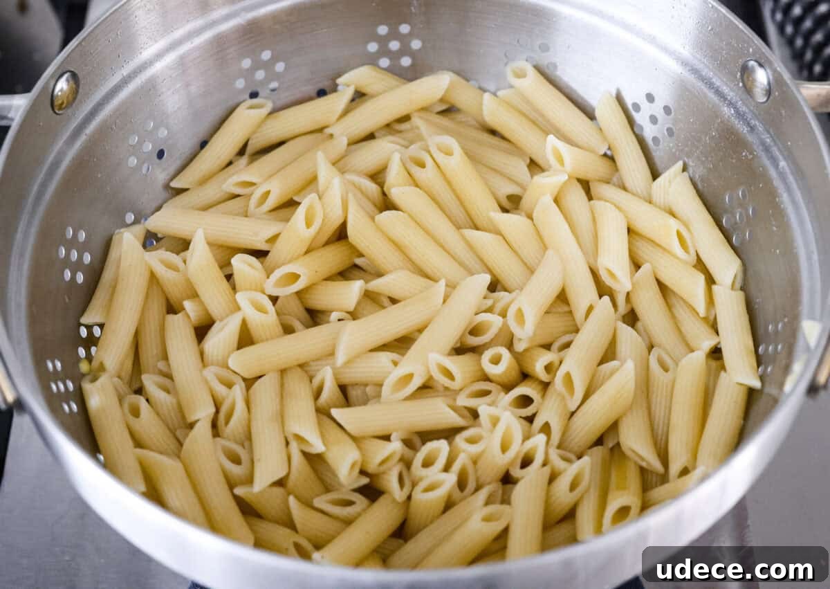 Creamy Baked Chicken Alfredo Pasta Casserole Recipe 2 Cooked penne pasta in a colander.