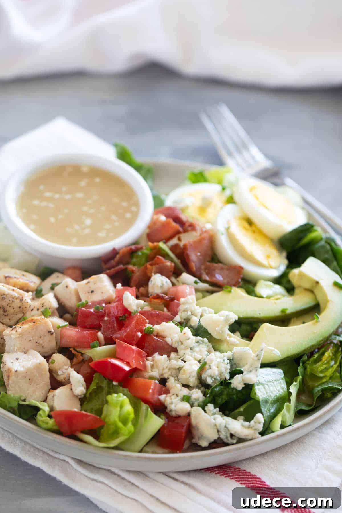 Classic Cobb Salad Recipe with Chicken, Bacon & Avocado 6 Cobb Salad on a plate with ramekin of dressing on the plate.