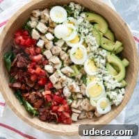 Classic Cobb Salad Recipe with Chicken, Bacon & Avocado 7 Cobb Salad with toppings arranged in lines on top in a large bowl.