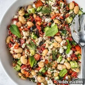 4 Mediterranean Meal Plans for Seasonal August Eating 6 Greek butter bean salad garnished with fresh mint leaves and fresh dill fronds in a large serving bowl.