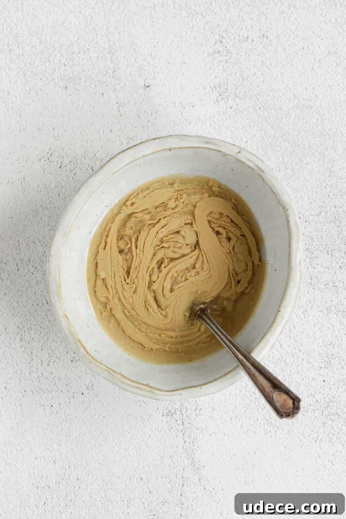Maple Tahini Dressing Recipe for Salads and Bowls 5 Maple tahini dressing ingredients being mixed in a shallow bowl.