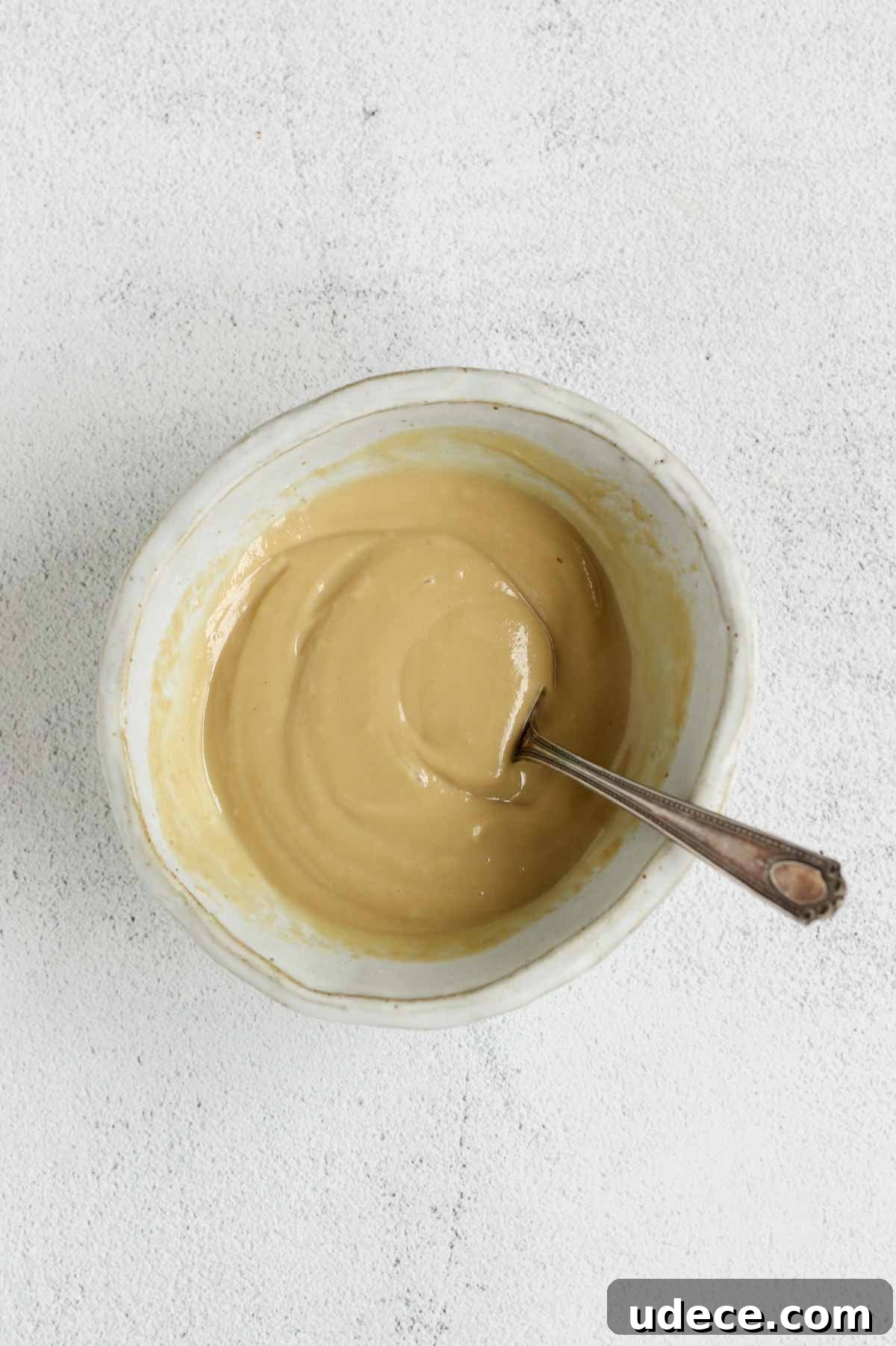 Maple Tahini Dressing Recipe for Salads and Bowls 6 Maple tahini dressing mixed in a shallow bowl with a fork in the bowl.