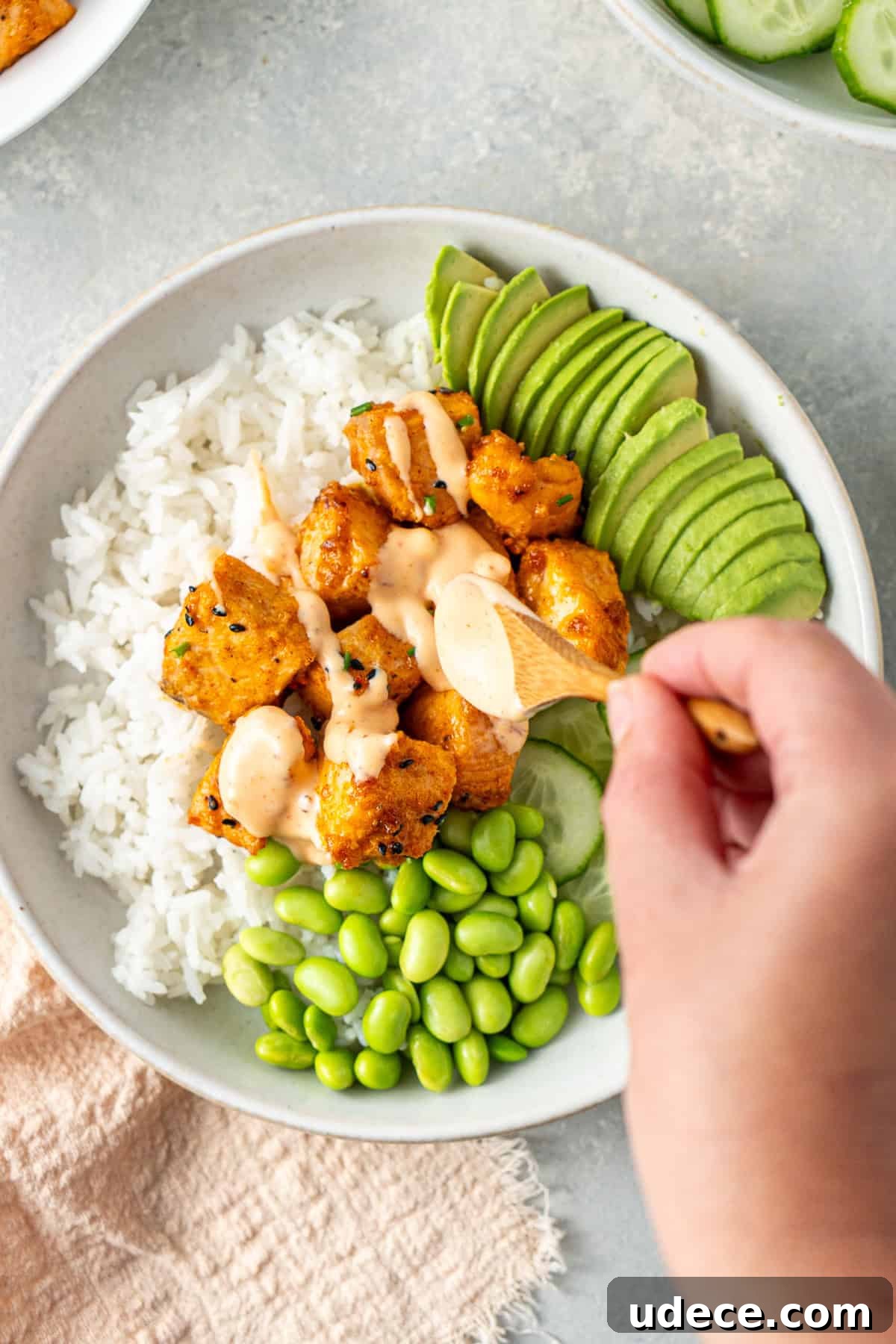 Spooning the bang bang sauce over the salmon rice bowl.