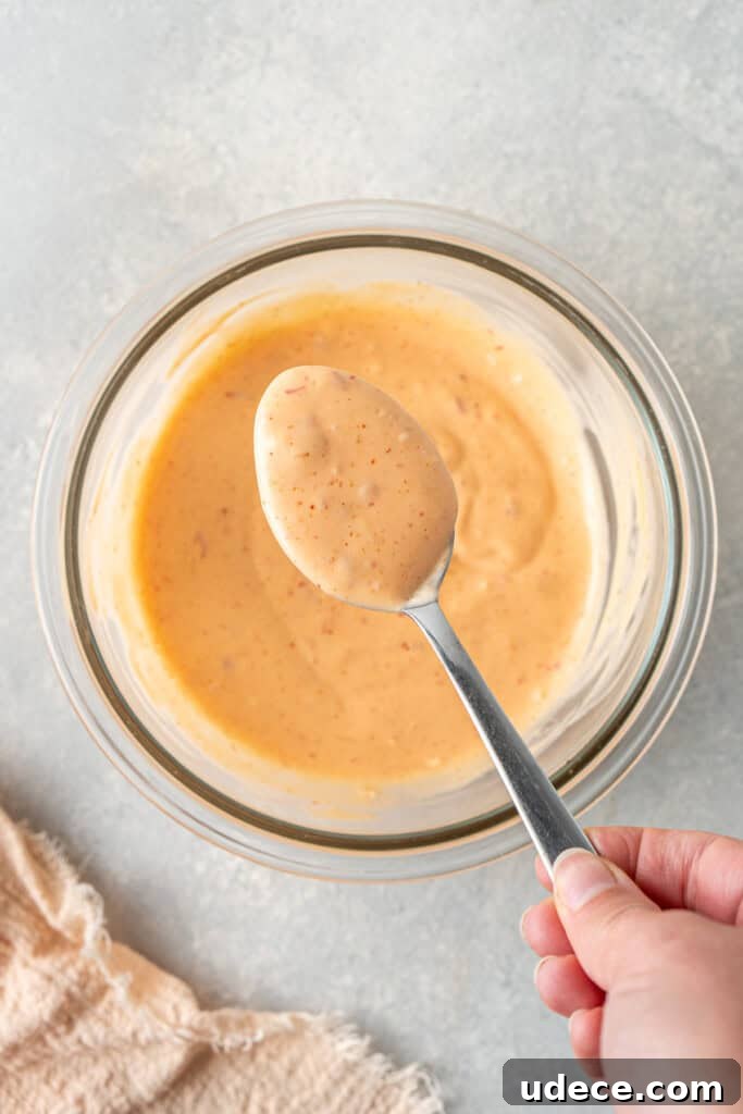 A spoon mixing together the bang bang sauce in a bowl.